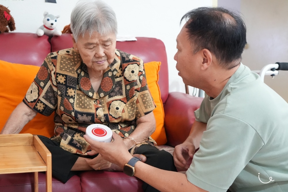 Personal Alert Buttons: How Seniors And Caregivers Are Achieving Greater Peace Of Mind - Retiree Jimmy Wan showing his mother the BOP device